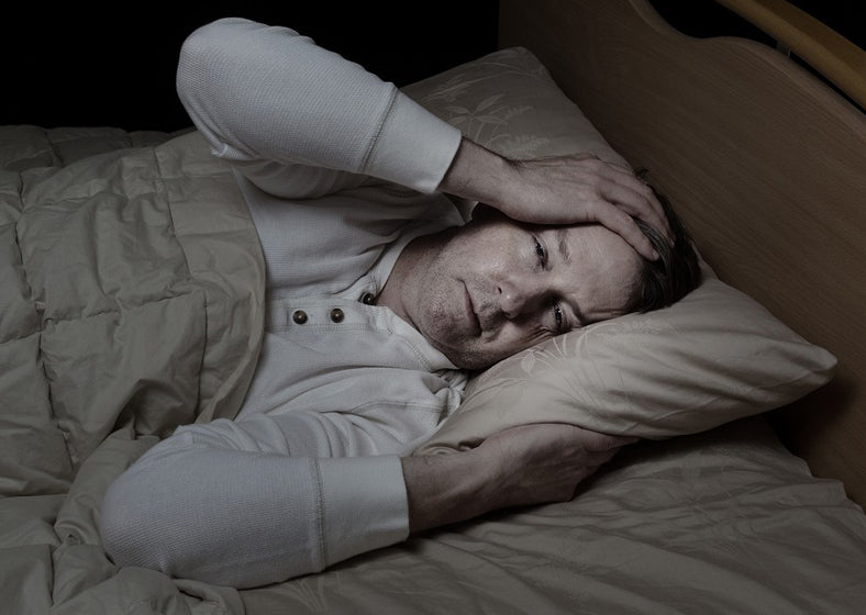 A man experiencing night sweats after sleeping on a traditional mattress