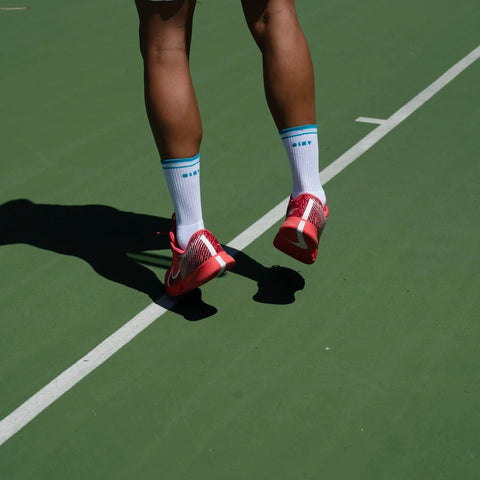 Why do tennis players wear long socks? Player serving with men's tennis socks.