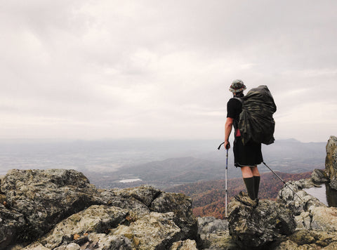 man looking out at mountains with trekking poles