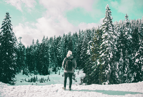 man walking in the middle of snowy forest