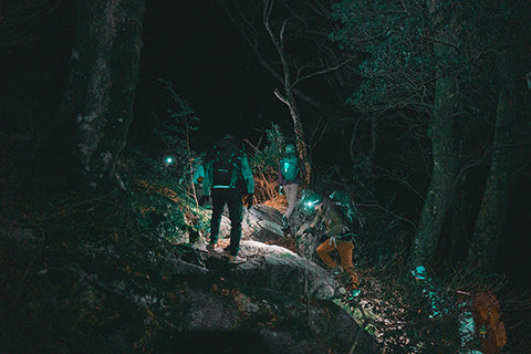 men hiking with headlamps at night