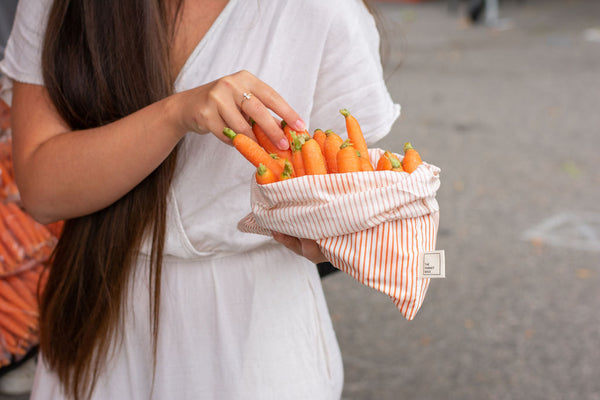 Model places fresh carrots into a Market Bags reusable produce bag.