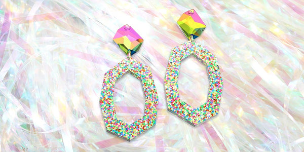 pair of glitter rainbow crystal Jaci earrings on iridescent background