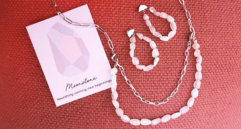 Neomi moonstone earrings and necklace on red background with card