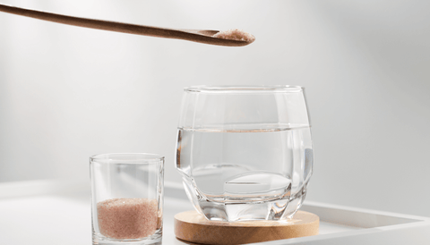 Imagen de un vaso de agua con un poco de sal rosa