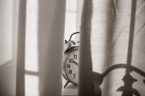 A desktop clock partially obscured by a curtain