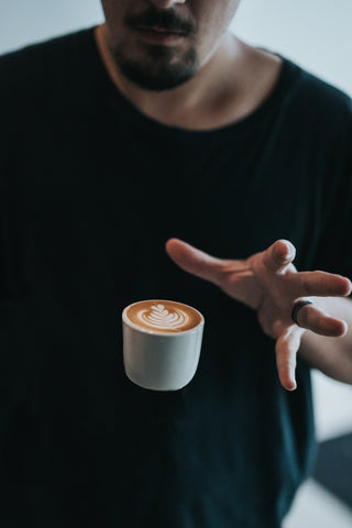 A man letting go of a cup of coffee.