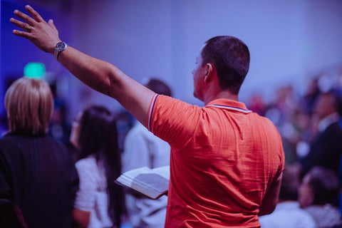 Man in church worshipping and holding the Bible.