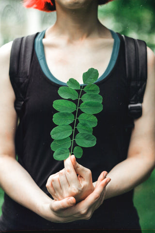 Woman holding moringa leaves in front of her chest.