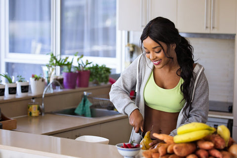 Woman in workout clothes preparing a meal.