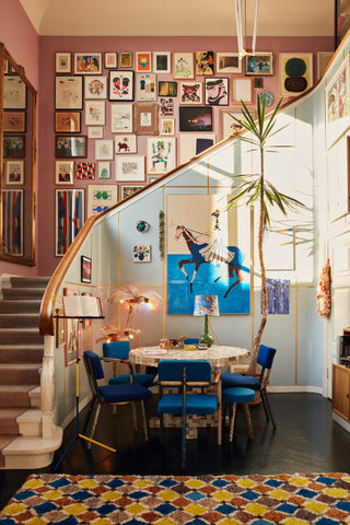 Blue and pink living space with large gallery wall in the staircase in a colorful art-filled home