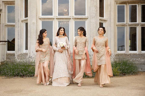 Four bridesmaids in pink and gold outfits, elegantly complementing the cheap wedding guest dress.