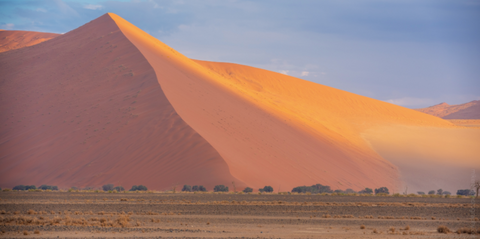 large sand dune with sun shining on it