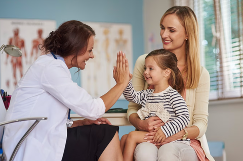 A Little Girl High Fives With A Female Pediatrician