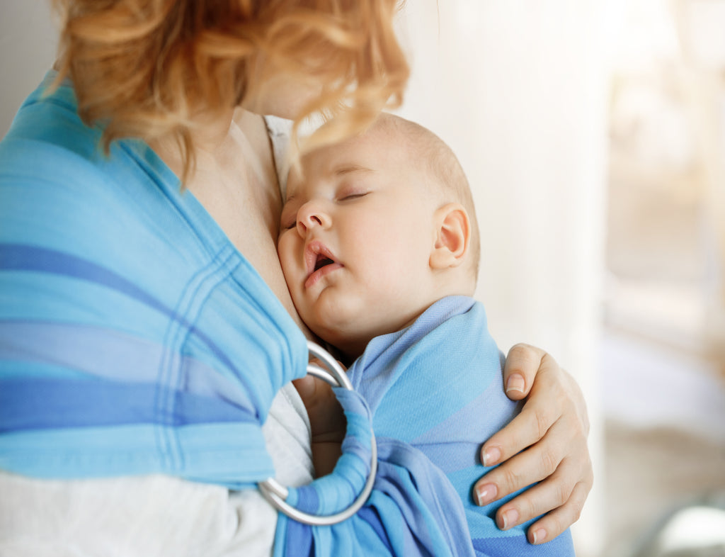 Innocent newborn boy having sweet dreams mother chest baby sling