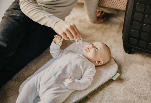 Mother Sitting On The Floor Coaxing Baby With Pacifier