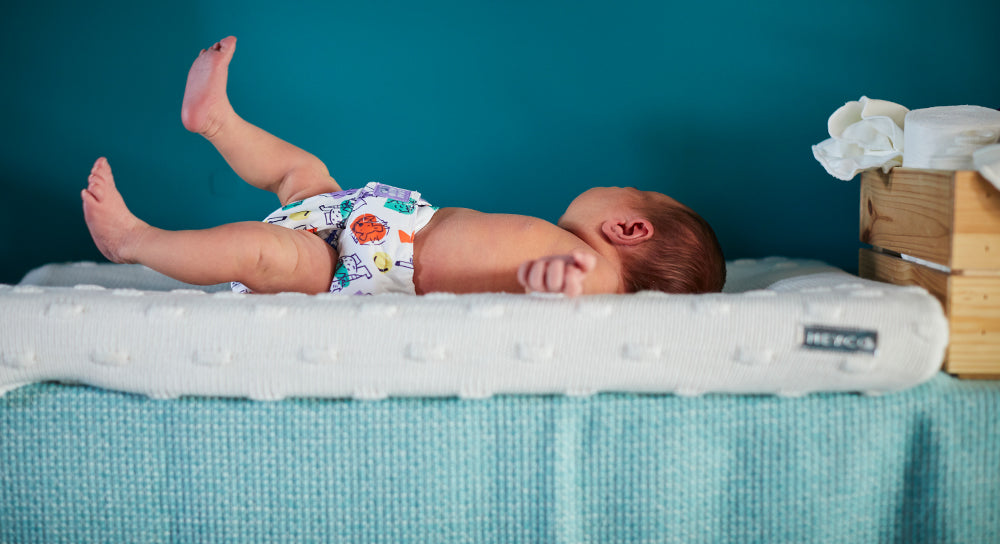 Baby on changing table wearing a reusable nappy