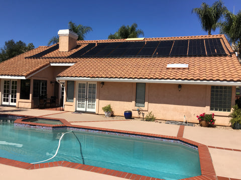 house with in ground pool with solar pool heating panels on roof