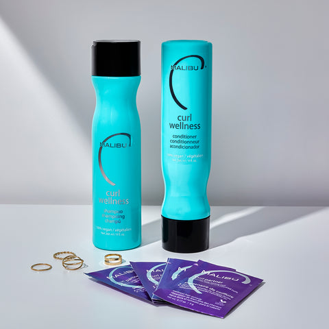 Curl Wellness Items with beauty accessories. Curl Wellness Shampoo, Curl Wellness Conditioner, and Curl Partner packets