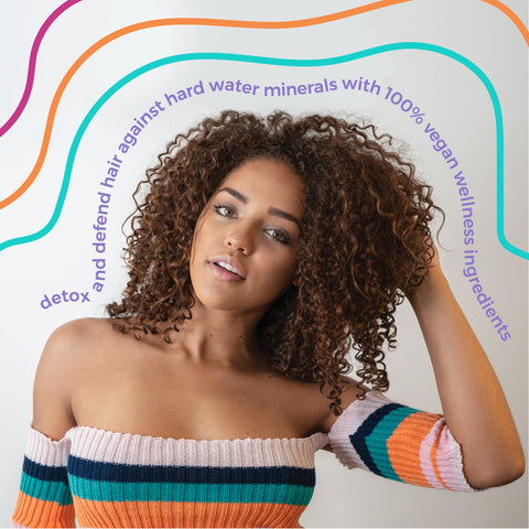 Girl with coiled, kinky-curly hair and text "Detox and defend hair against hard water minerals with 100% vegan wellness ingredients"