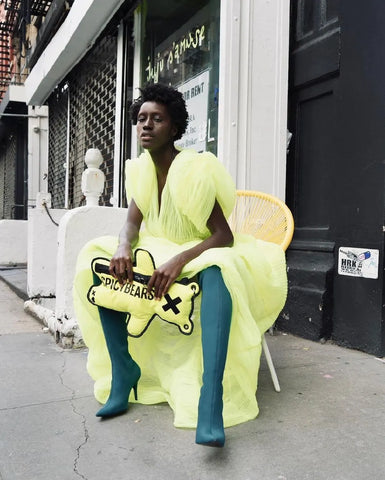 Beautiful model wearing neon lemon bright dress and carrying bear shaped crossbody bag