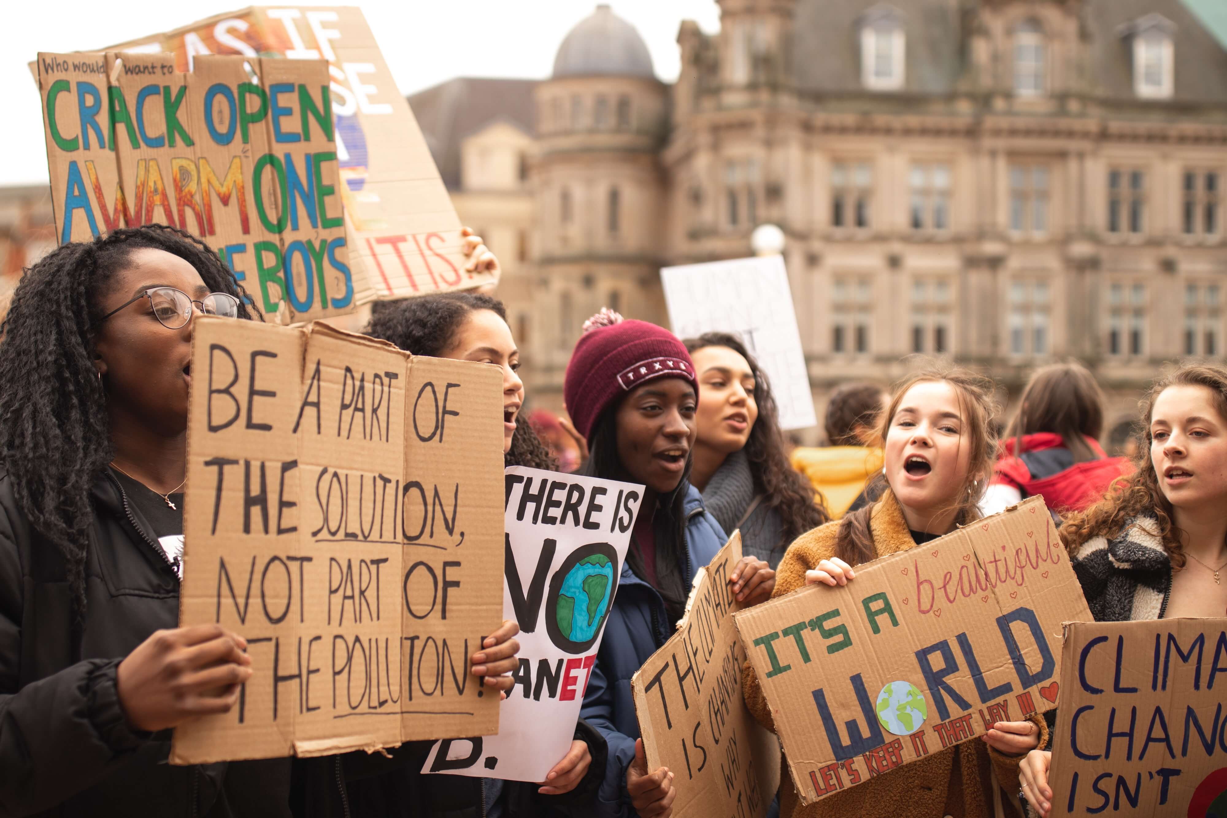 Image of young women attending a climate action protest holding signs urging climate action