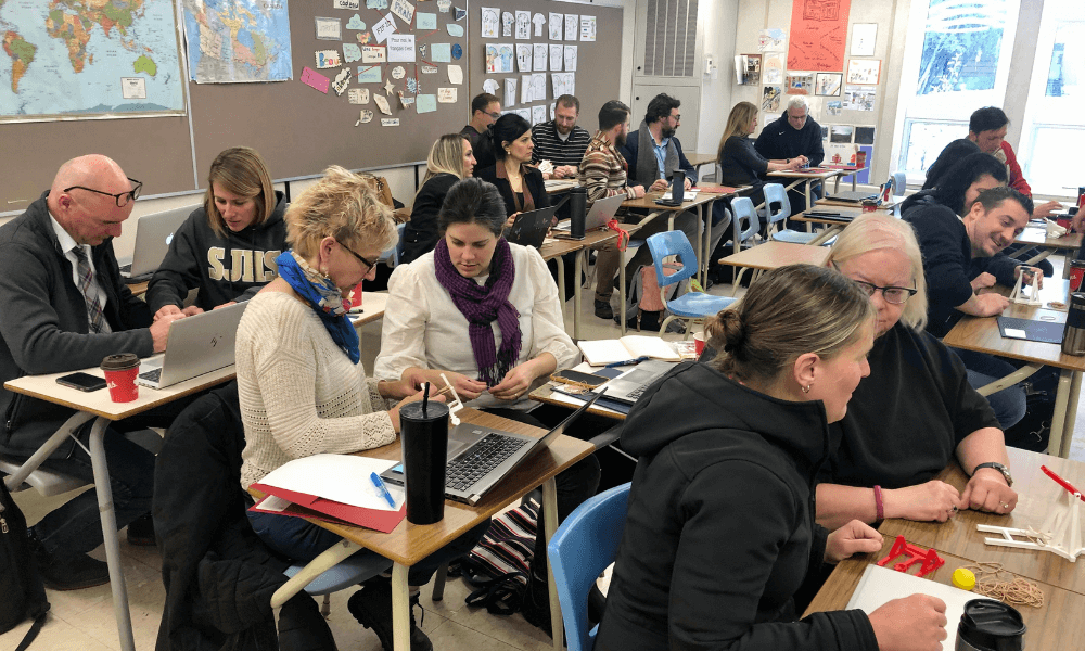 Image of teachers sitting in pairs at desks in a classroom participating in a professional development workshop