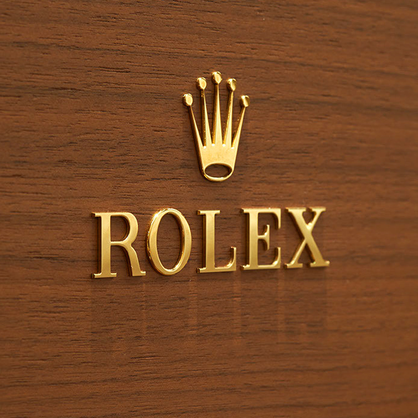 Rolex logo in gold on a wooden background