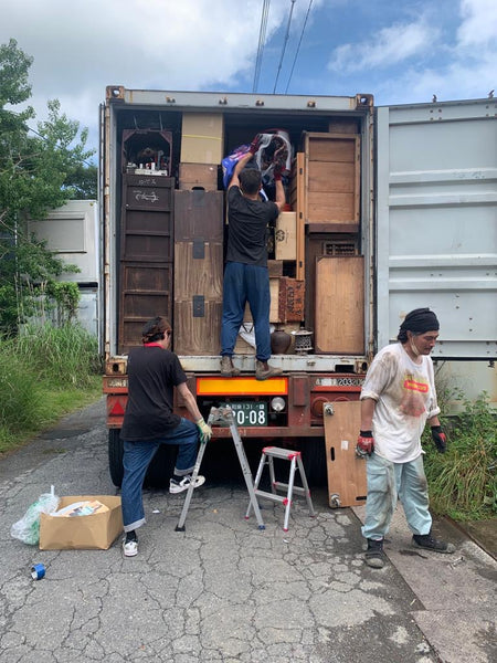 People packing up a container with furniture and other items