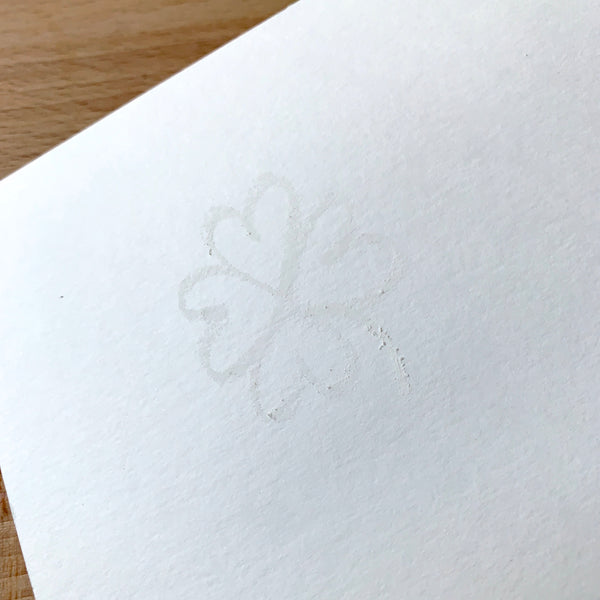 Faint image of a shamrock drawn in white crayon on white watercolour paper