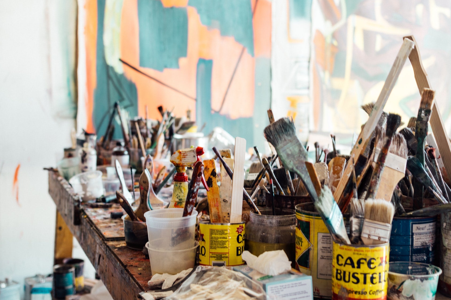 Image of messy artist studio with cans of paintbrushes filling the table