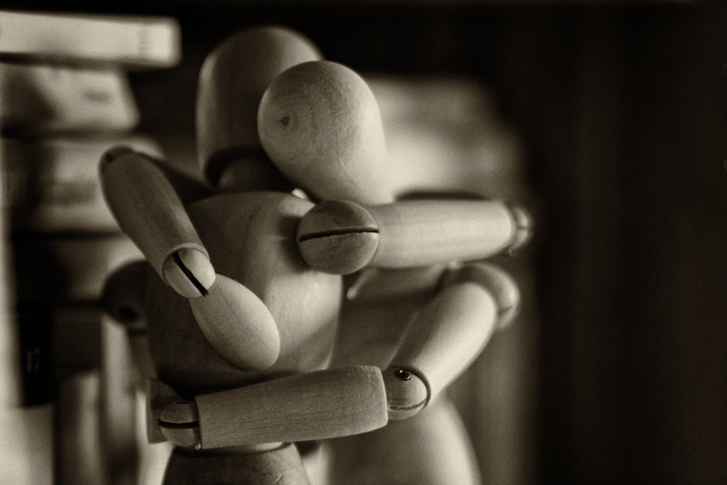 Two drawing figurines hugging each other in a black and white photo