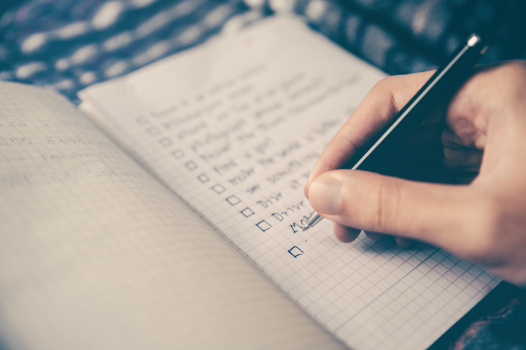 close up of person writing a to do list in a journal 