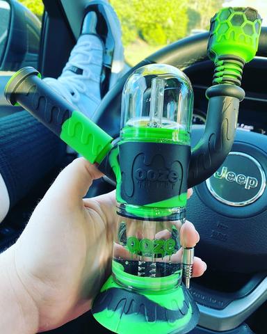 Holding OOZE 4 in 1 dab rig in car for smoking concentrates green and black