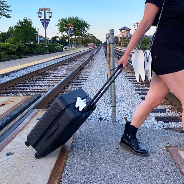 women crossing train tracks with suit case and tooth purse 