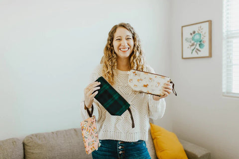 A woman holding two dumpling cosmetic on-the-go bags