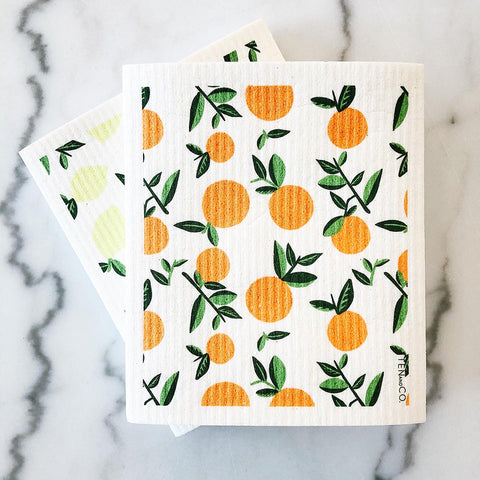 Orange and Lemon patterned sponge cloths on a marble countertop.
