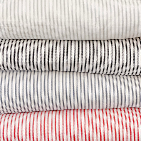 Stack of ticking stripe pillows in beige, black, navy and red stripe.