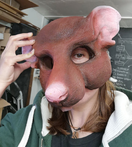 Brown painted rat folk mask being worn by an idiot in a green hoodie