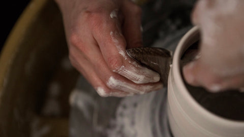 Close up of hands throwing a cup on the pottery wheel