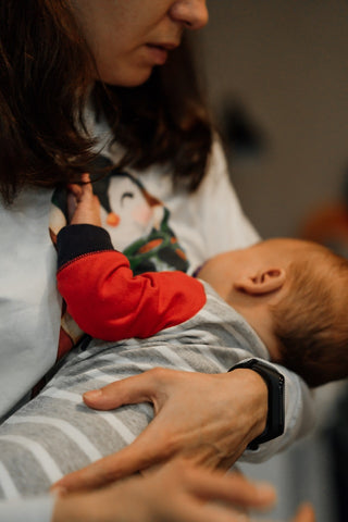 Une femme allaite son bébé dans ses bras.