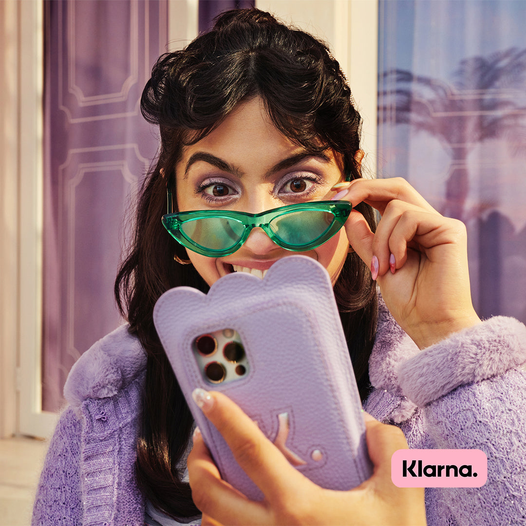 Woman wearing green glasses looking into phone Klarna logo