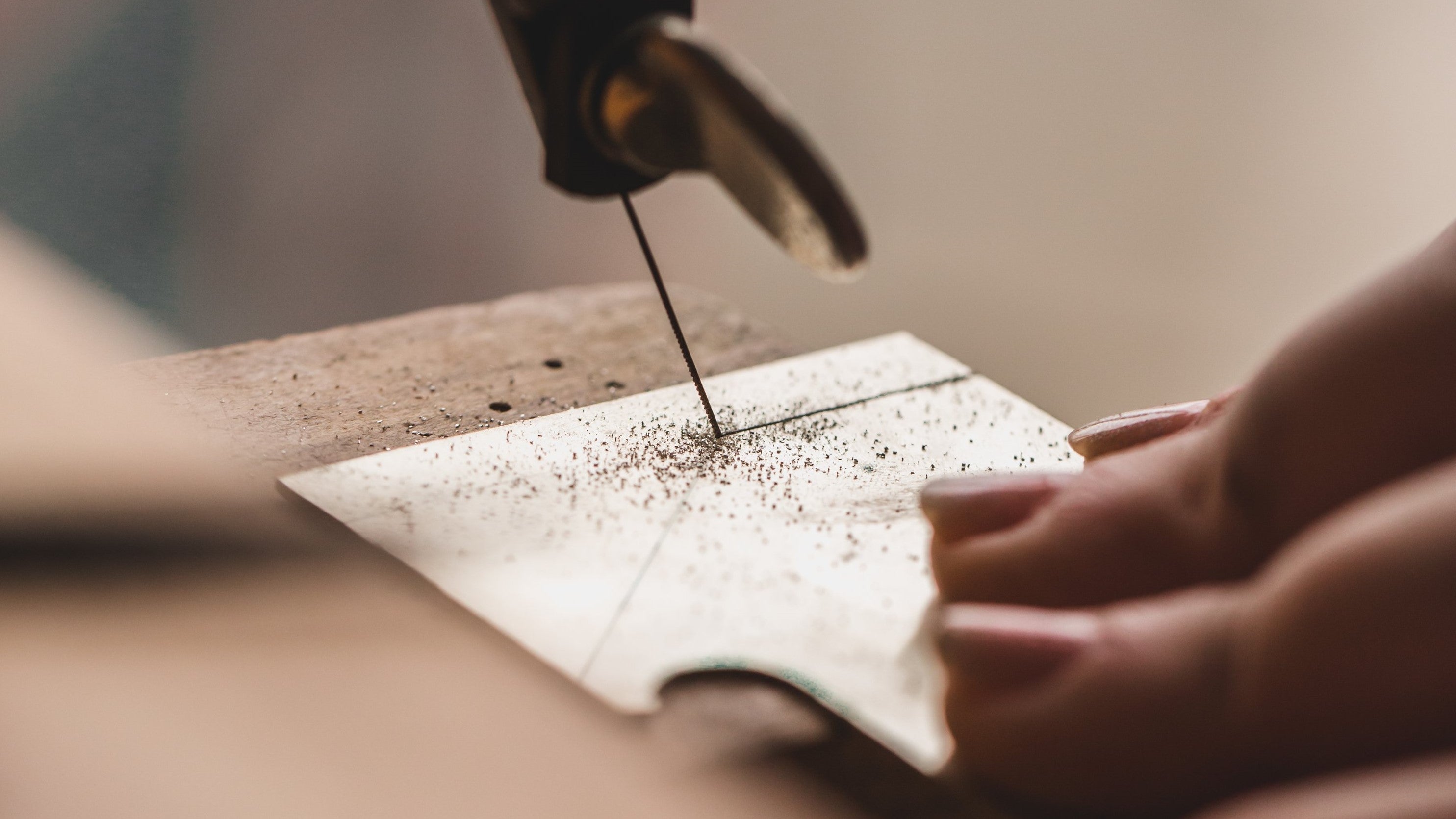 Goldsmith using a saw to cut through sheet of White Gold