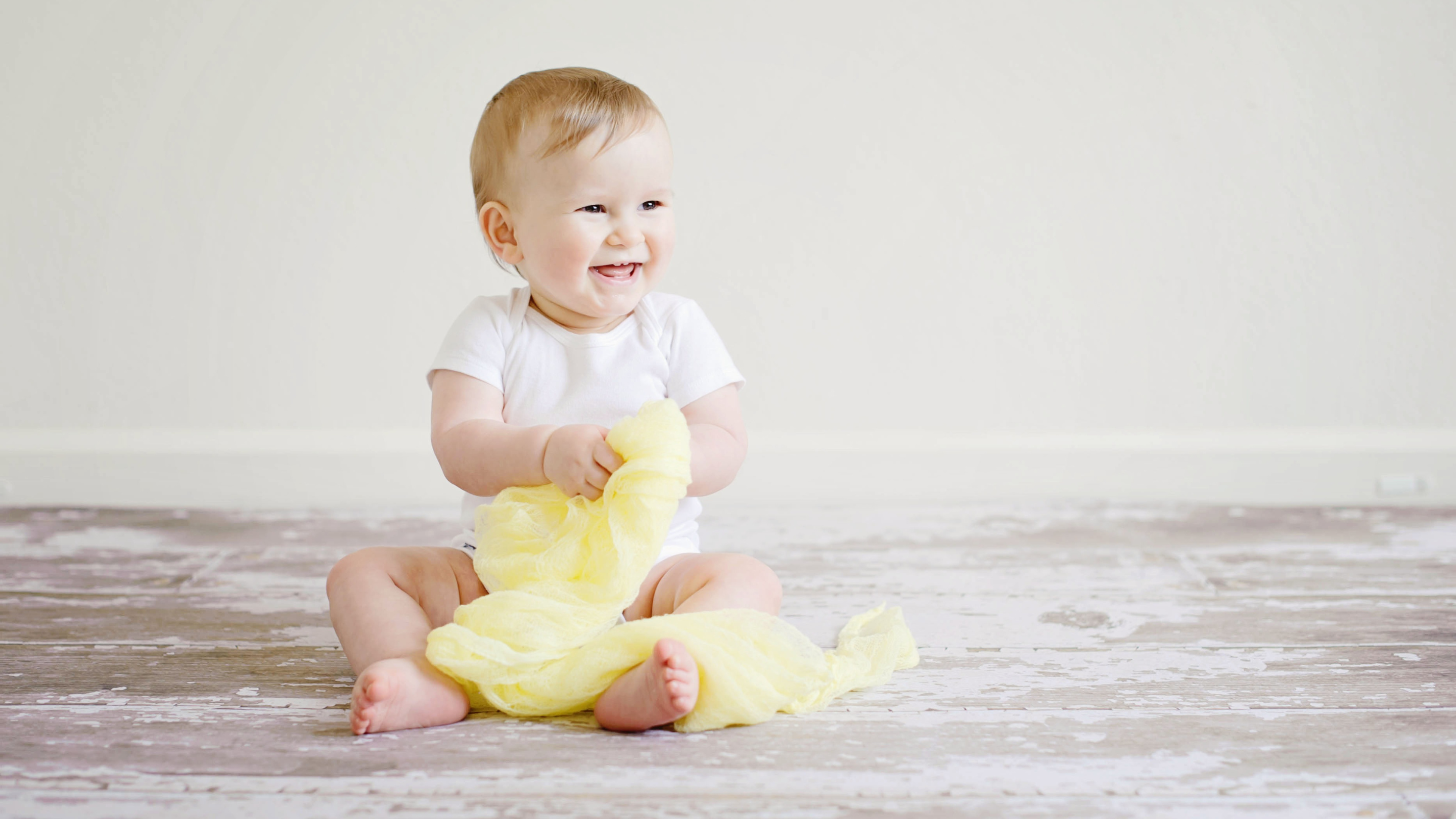 bébé assis avec une barboteuse jacadi blanche