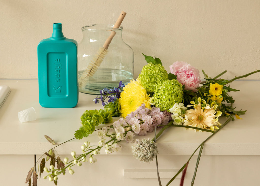 Blumen auf einem Schrank mit einer Vase daneben