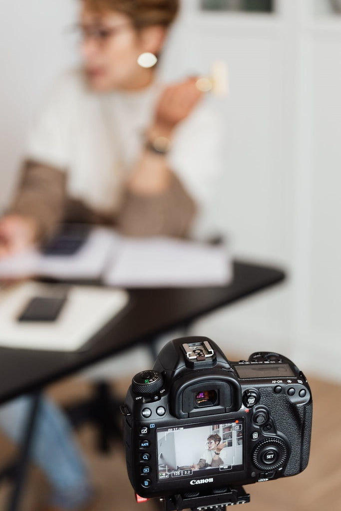 a digital camera with an image of a woman leading a meeting in the viewfinder