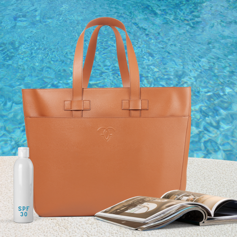 Indiana Laptop Tote sits by the pool with an open magazine and Sunscreen