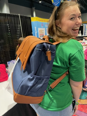 A Girl Scouts Troop parent showcases the Navy Wheels Up Roller Backpack at the Orlando Phenom Convention, July 22, 2023. Photo by Francine Farkas Sears