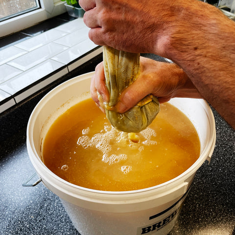 Squeezing the beer from the bag of dry hops