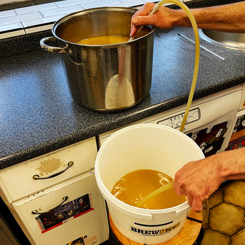 syphoning the wort from the stockpot into the fermenting bucket